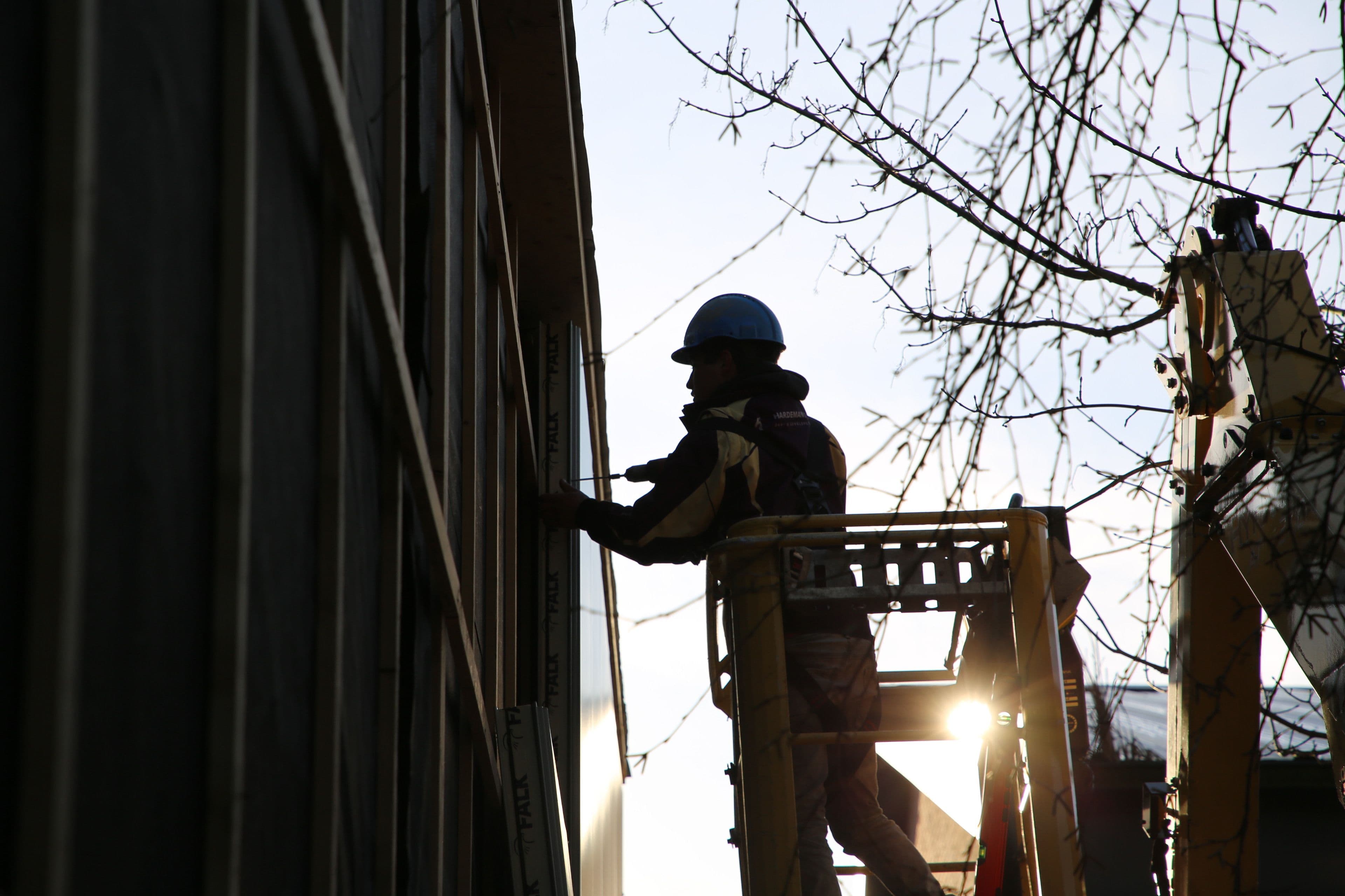 Monteur die wandpanelen monteert aan buitengevel van bedrijfspand