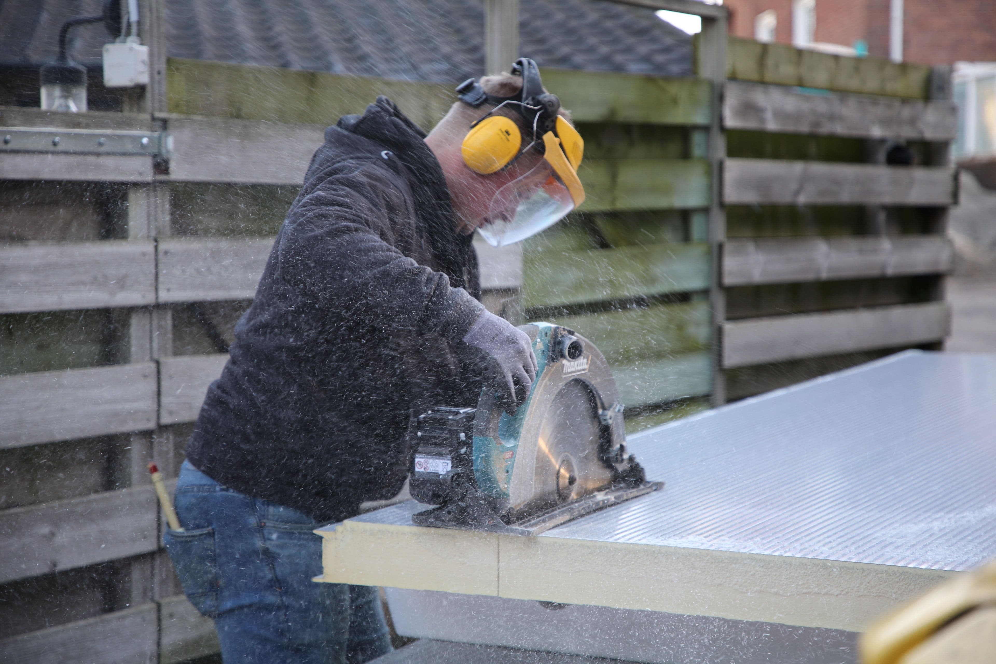 Monteur zaagt isolatiepaneel voor montage van PIR sandwichpanelen