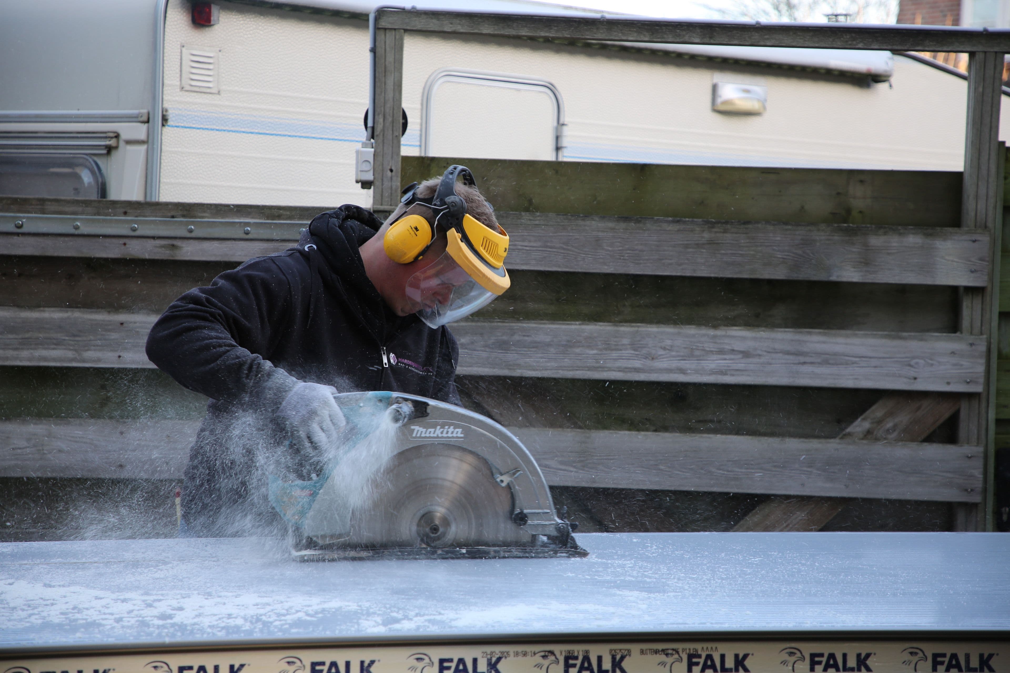Monteur zaagt sandwichpanelen op maat voor montage op een bedrijfshal
