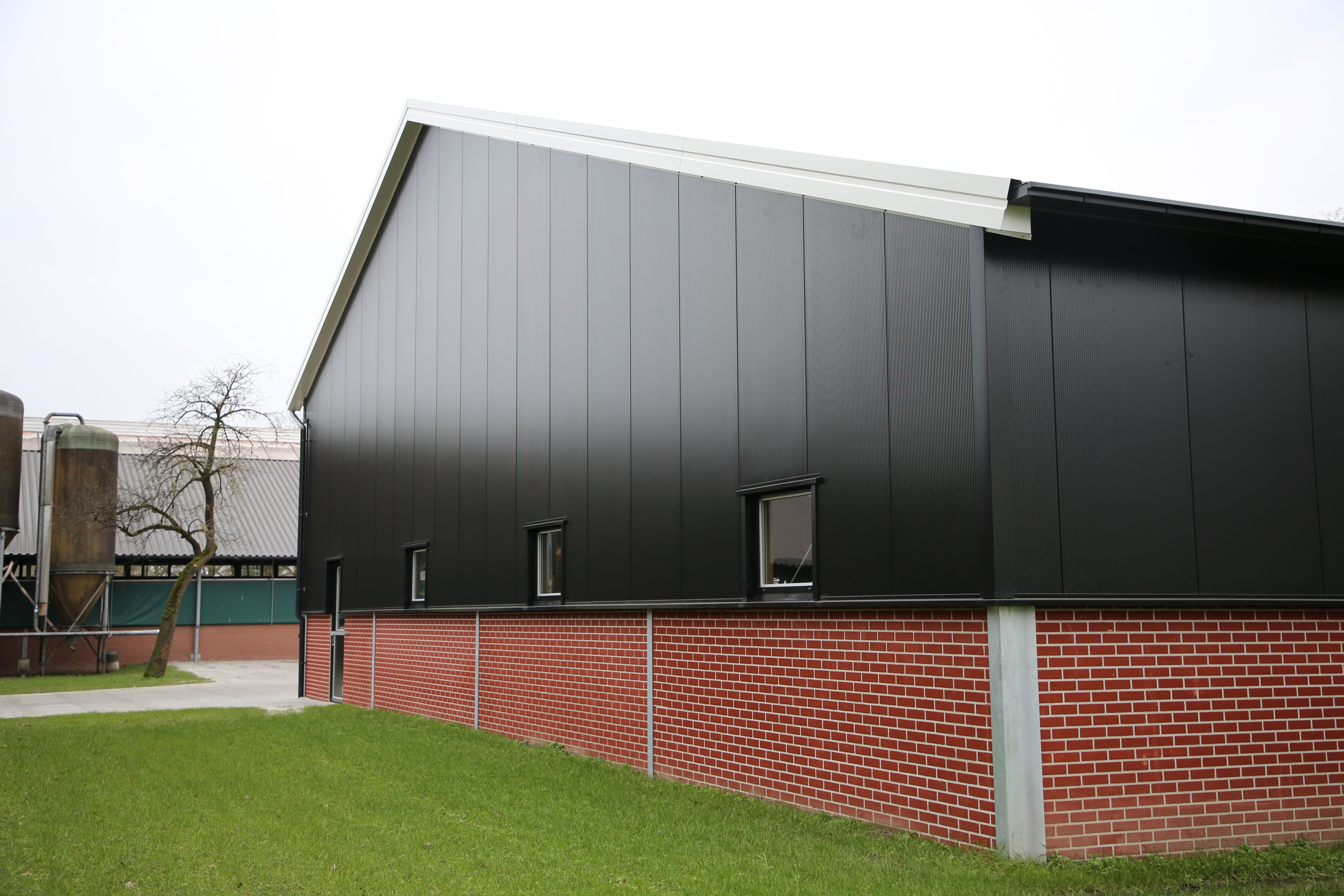 Zijgevel van de machineberging van Haamberg in Fleringen met zwarte sandwichpanelen