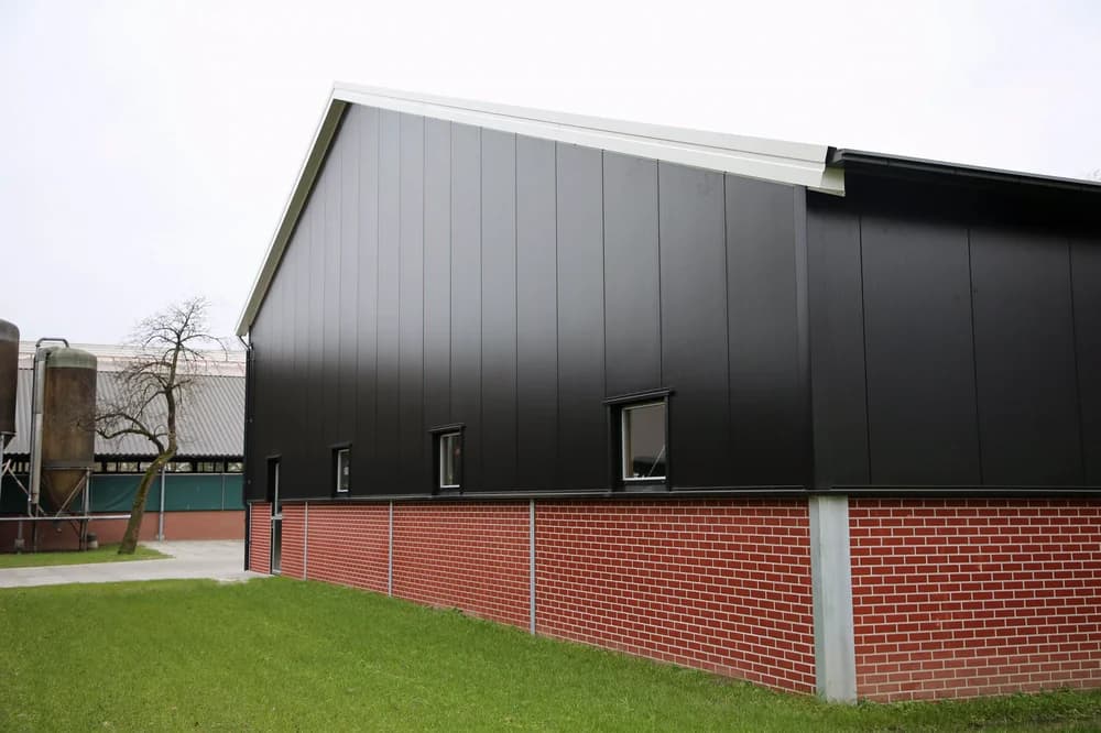 Zijgevel van de machineberging van Haamberg in Fleringen met zwarte sandwichpanelen