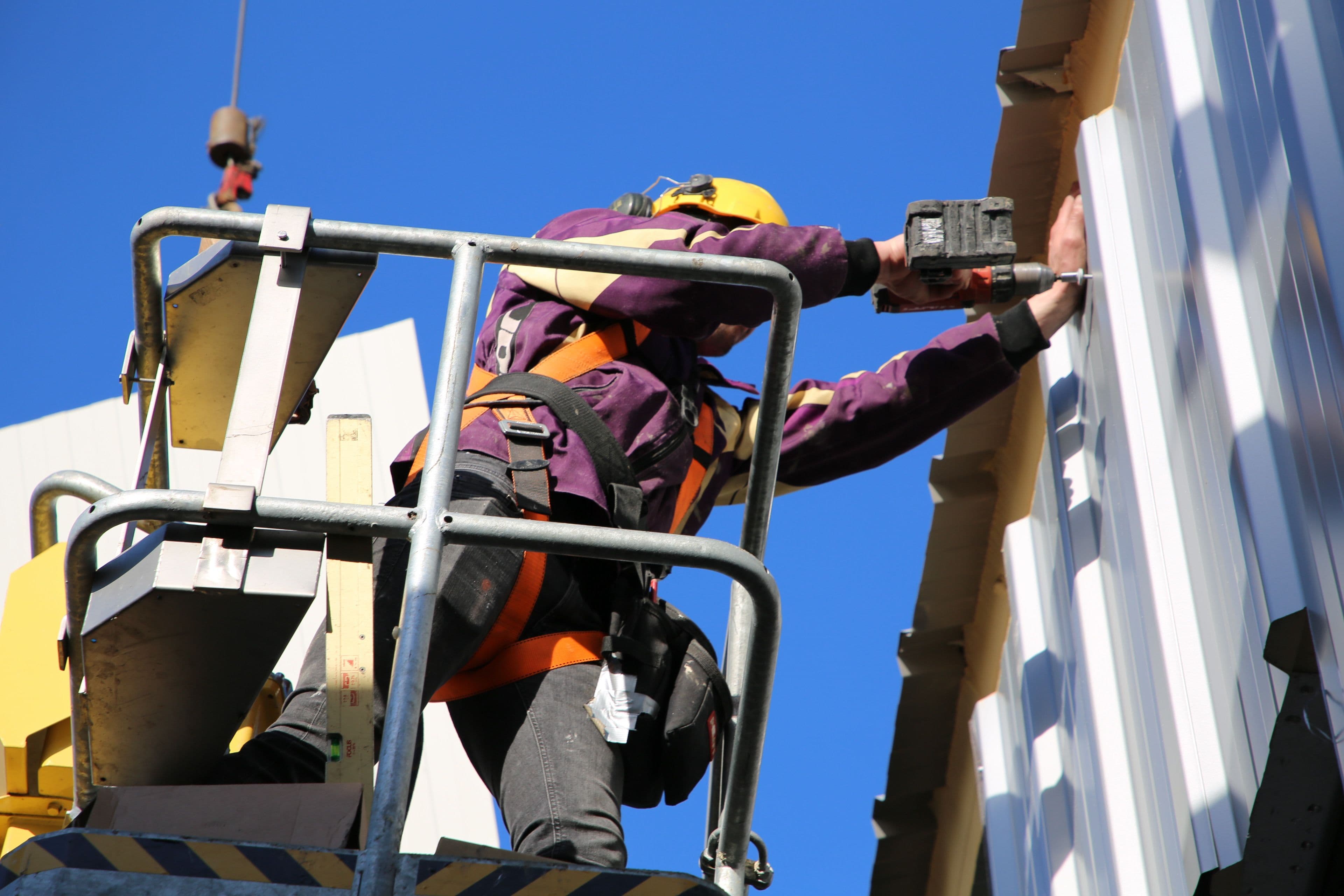 Monteur van Hardeman Isolatie monteert gevelbekleding met hoogwerker op bedrijfspand