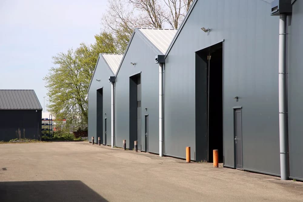 Bedrijfshallen in Bemmel met grijze gevelbekleding, overheaddeuren en vernieuwde dakranden.