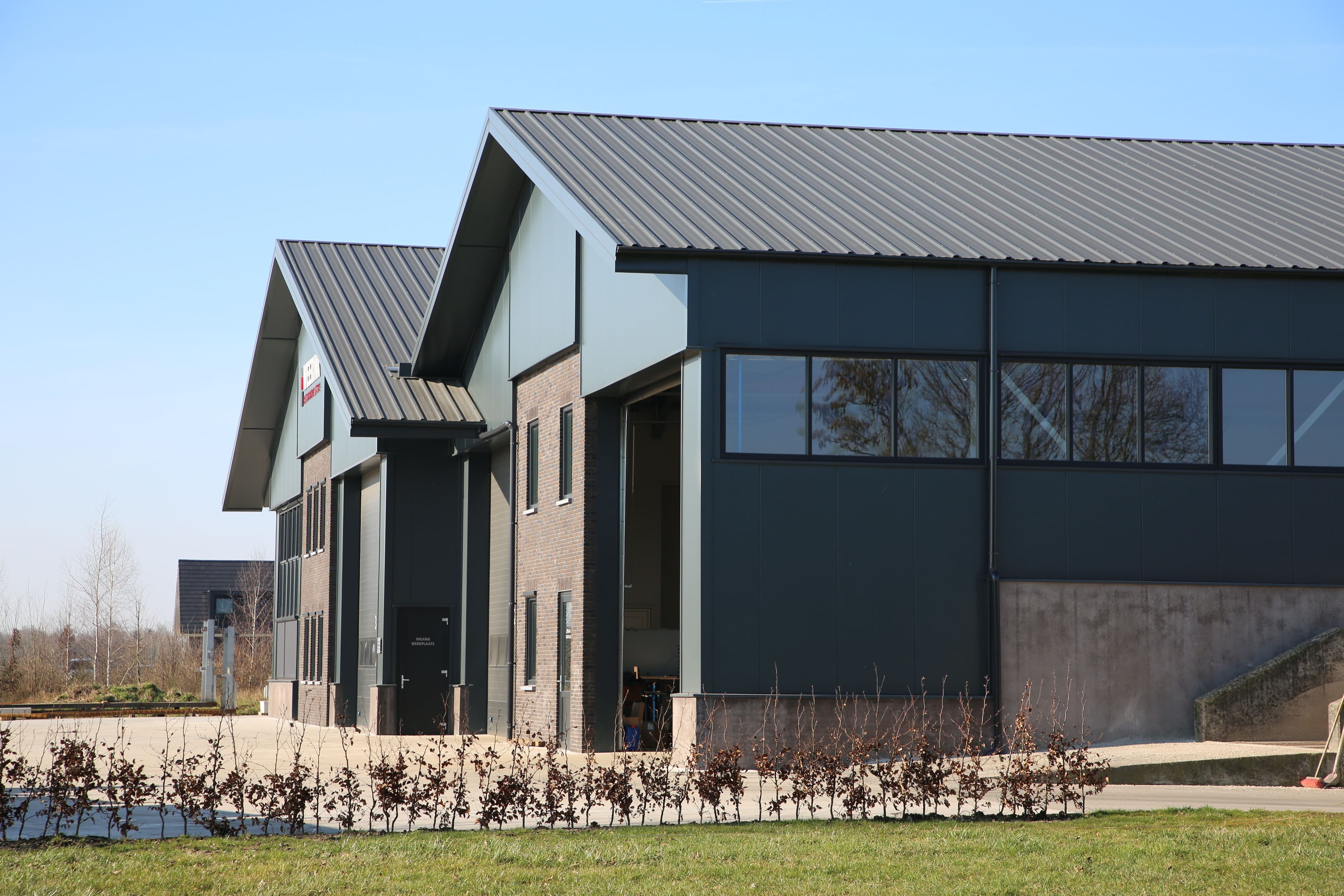 Gevelrenovatie van bedrijfshal met donkere geïsoleerde gevelpanelen