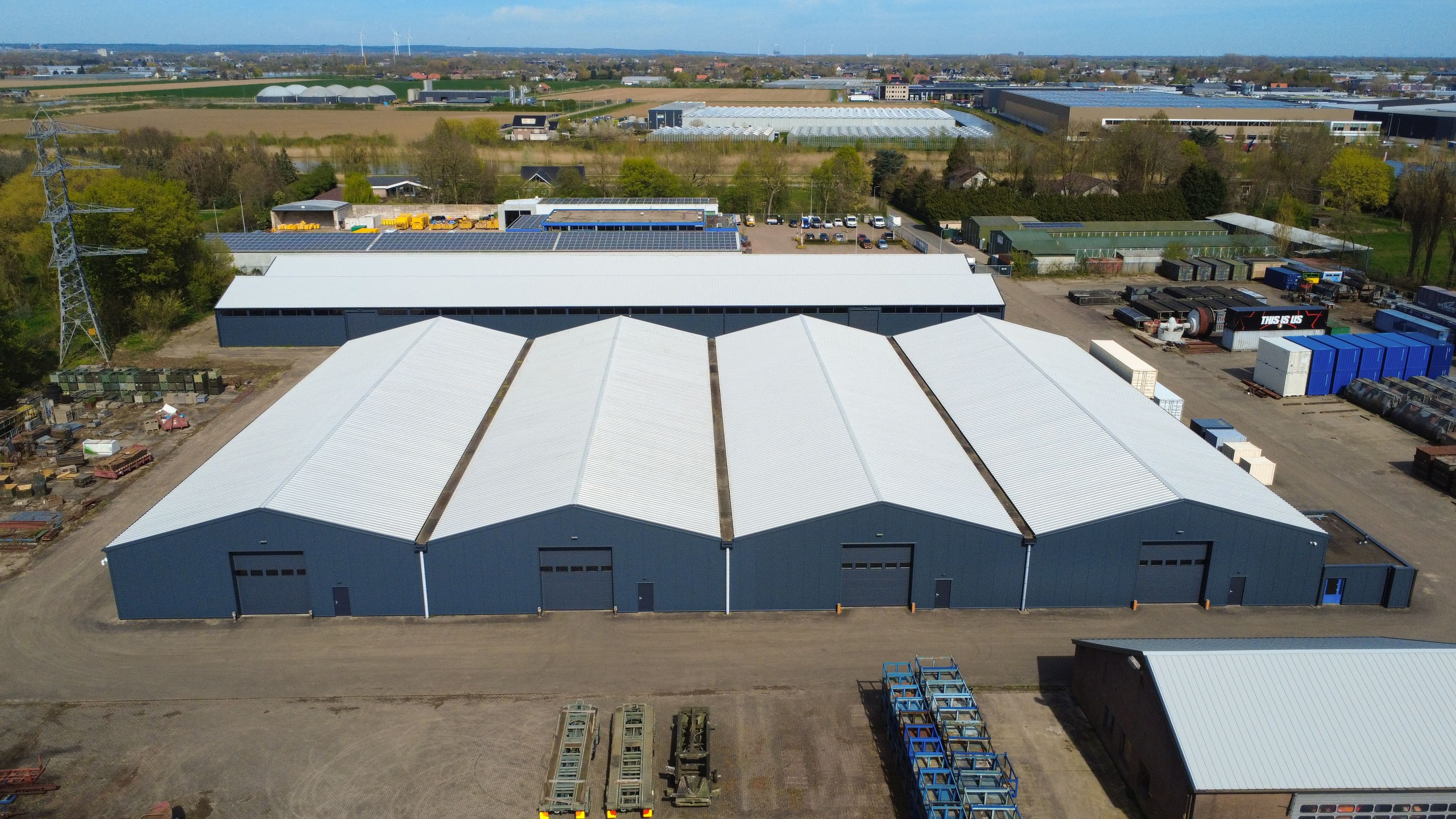 Luchtfoto van bedrijfshallen in Bemmel met vernieuwde witte dakbekleding en grijze gevels.