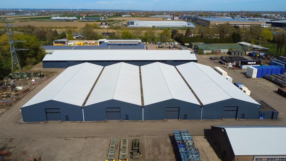 Luchtfoto van bedrijfshallen in Bemmel met vernieuwde witte dakbekleding en grijze gevels.