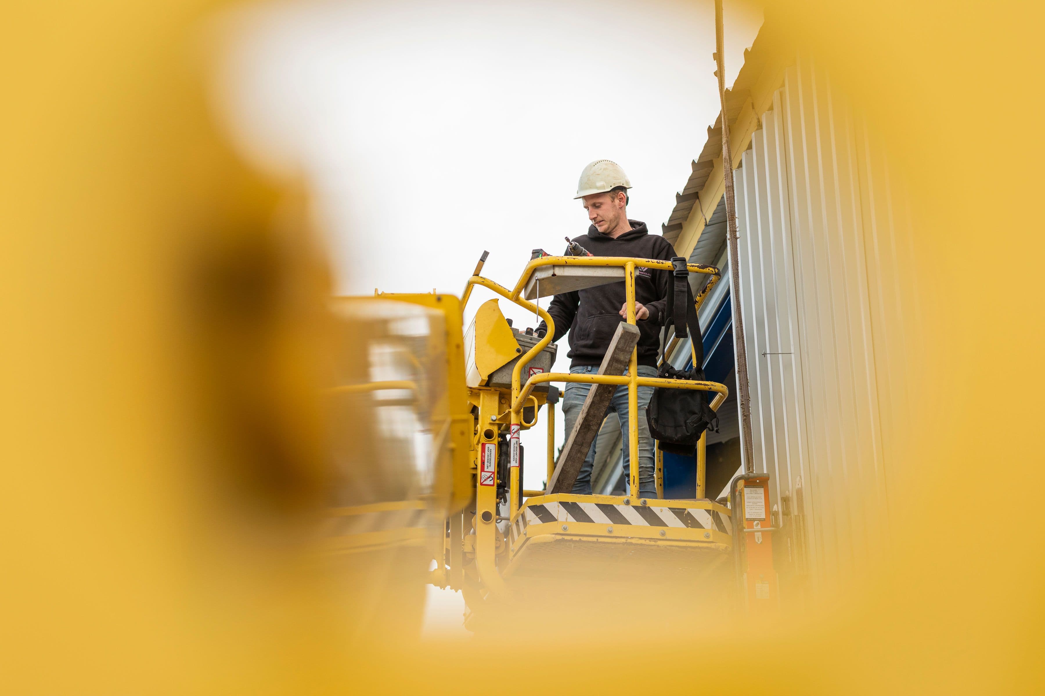 Monteur in hoogwerker tijdens montage van gevelpanelen