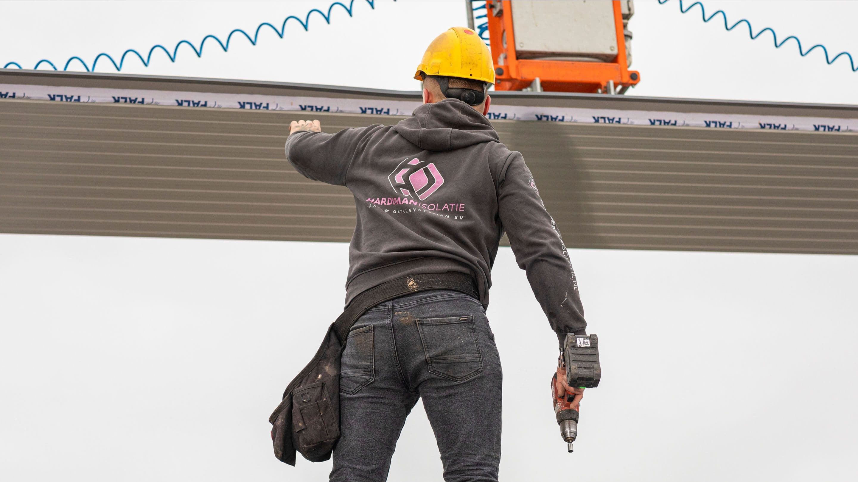 Monteur plaatst nieuw geïsoleerd dakpaneel tijdens dakrenovatie