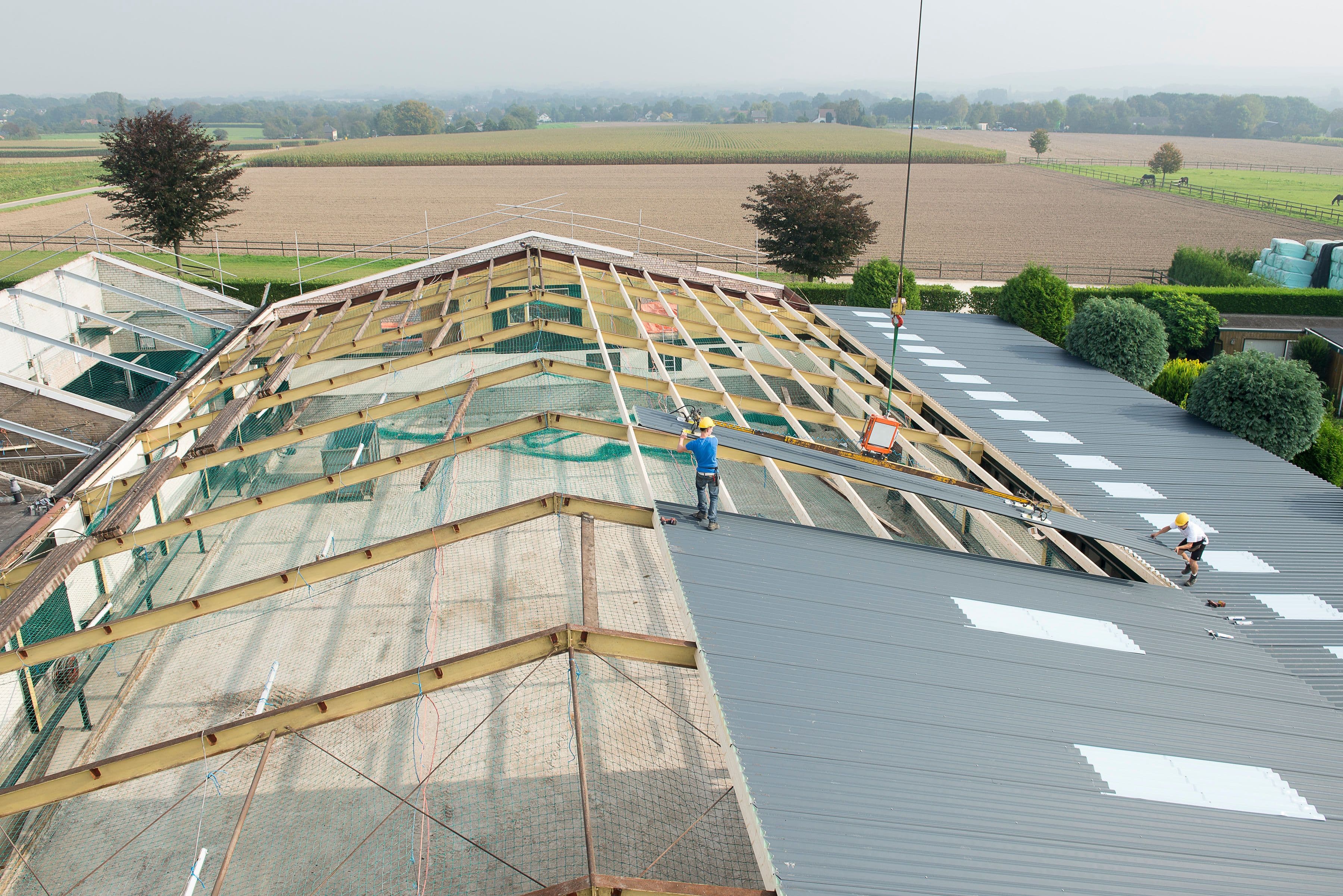 Dakrenovatie van een bedrijfshal waarbij oude dakplaten worden vervangen