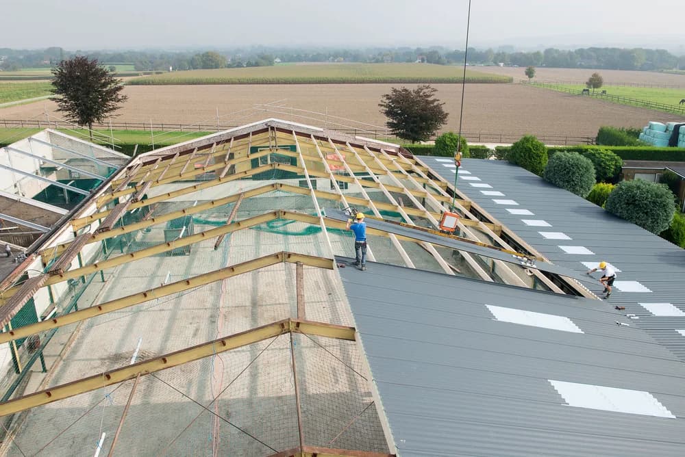 Dakrenovatie van een bedrijfshal waarbij oude dakplaten worden vervangen
