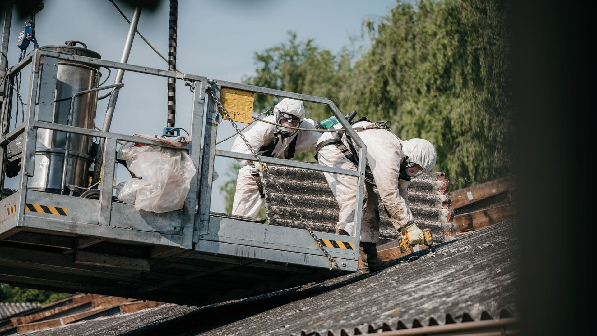 Specialisten verwijderen asbest van een dak met beschermende kleding en maskers