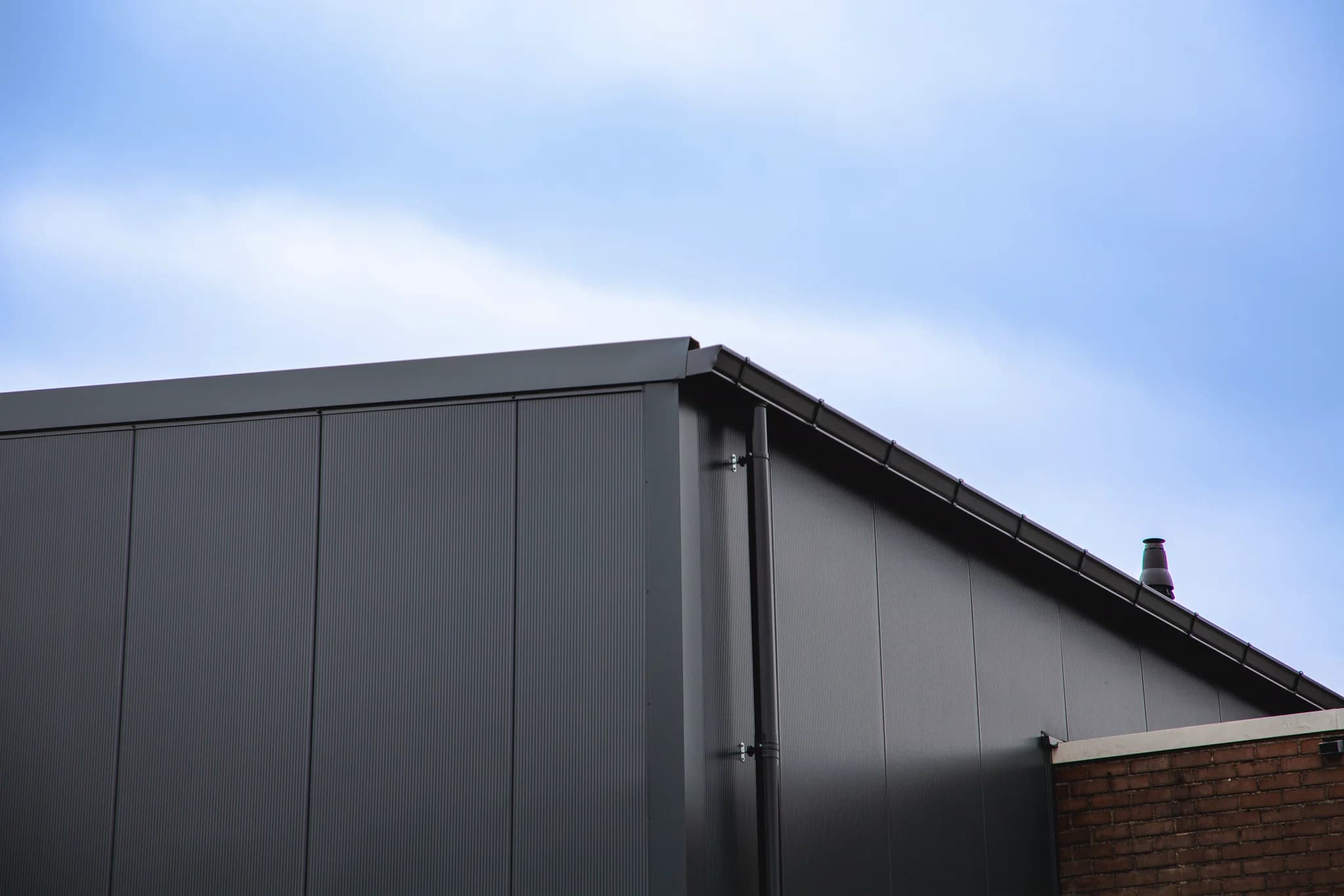 Nieuwe geïsoleerde dak- en gevelbeplating van een bedrijfshal aan de Hermesweg in Baarn, gerealiseerd door Hardeman Isolatie.