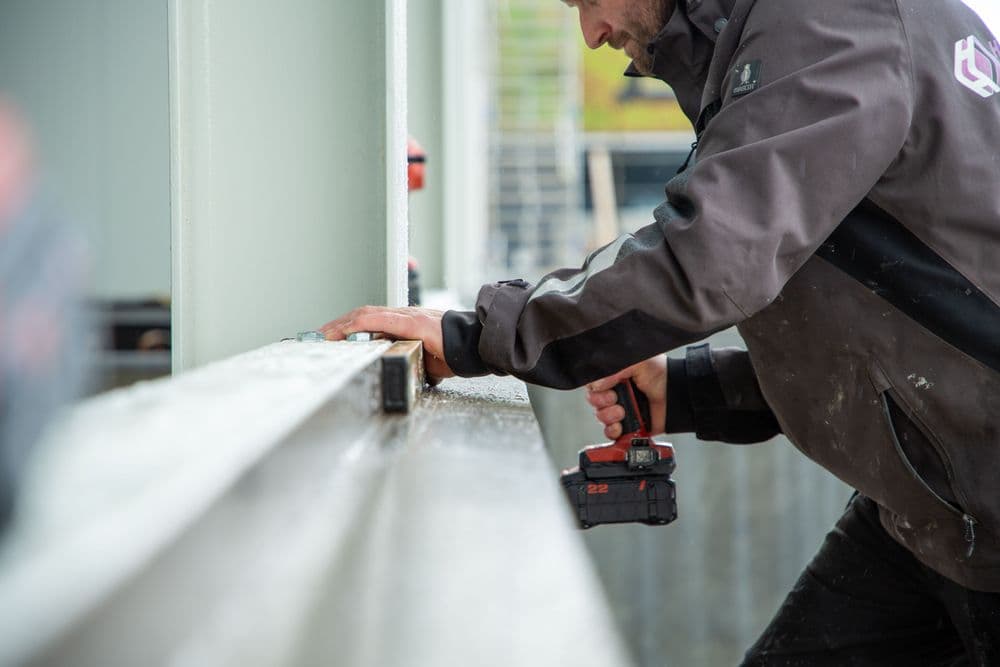 Monteur bevestigt gevelbekleding met een accuschroefmachine.
