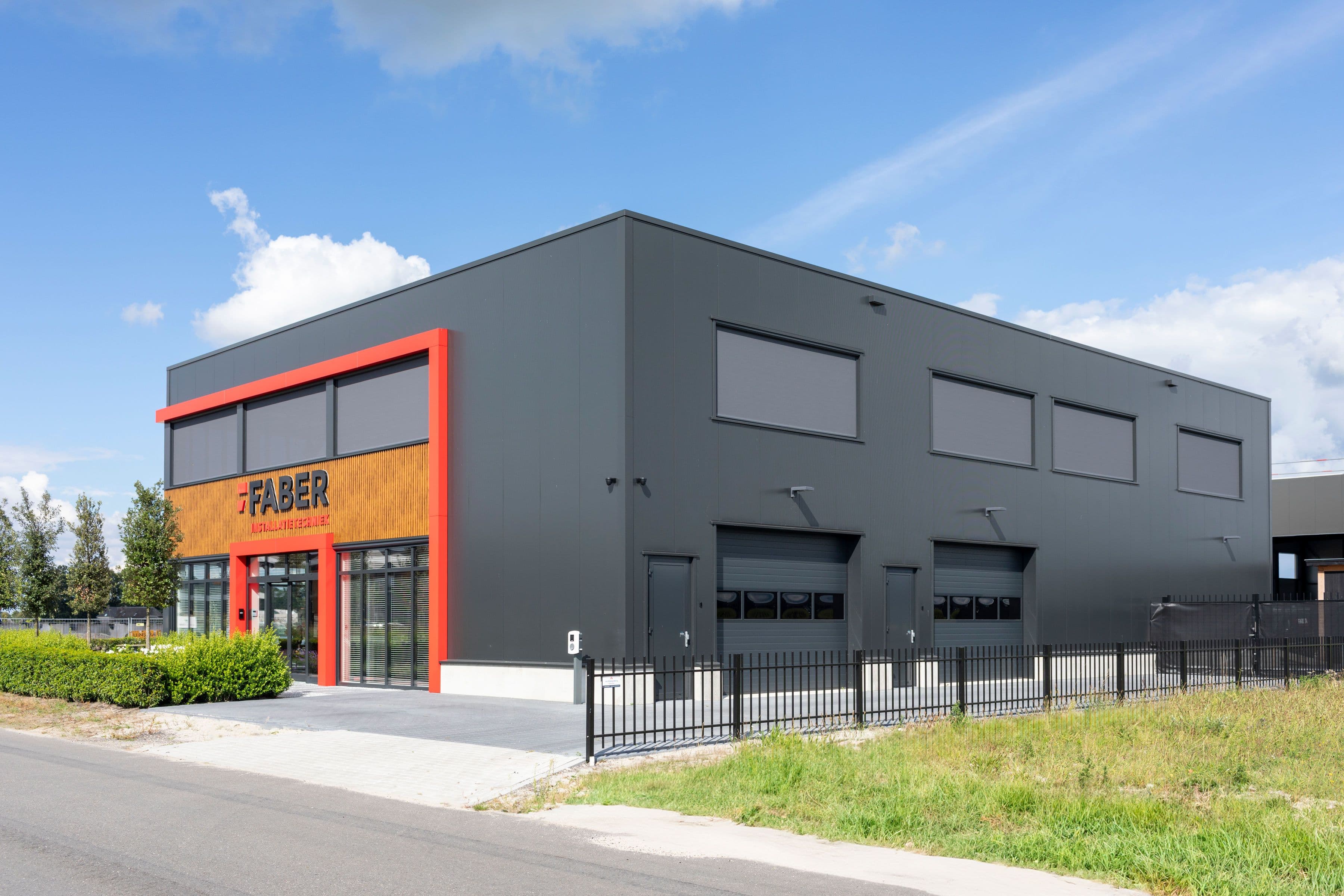 Bedrijfspand van Faber Installatietechniek in Elburg met sandwichpanelen en rood composiet gevelkader