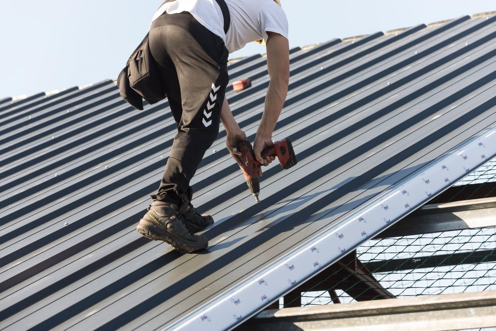 Monteur tijdens dakrenovatie met montage van metalen dakplaten